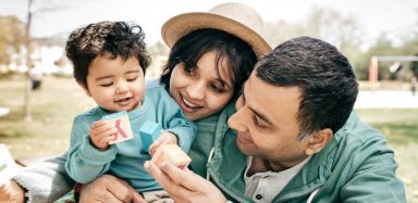Two parents playing with blocks with their toddler.